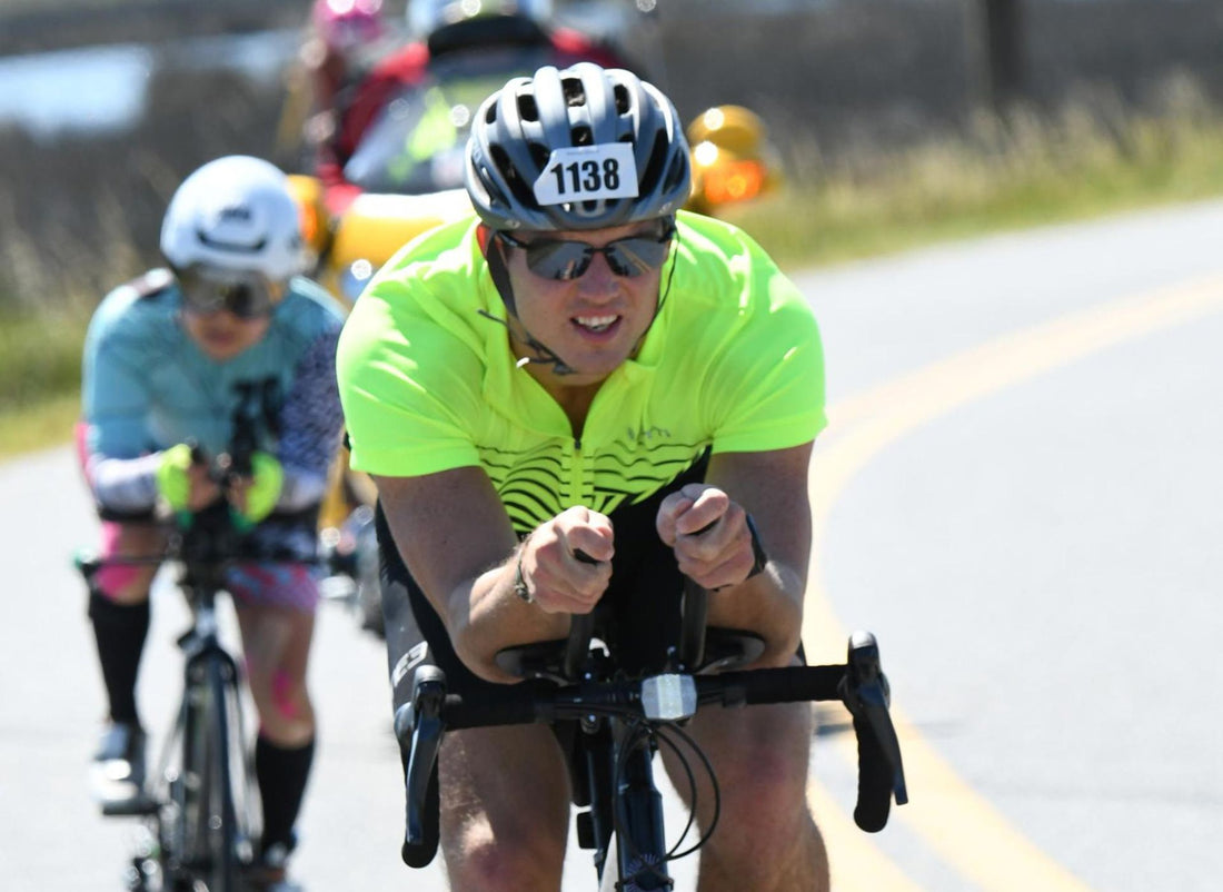 Founder of Simpl., Steve Onak, competing during his first Ironman. Image illustrates Onak riding in the front of a pack of cyclists in Cambridge, Maryland.