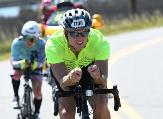 Founder of Simpl., Steve Onak, competing during his first Ironman. Image illustrates Onak riding in the front of a pack of cyclists in Cambridge, Maryland.